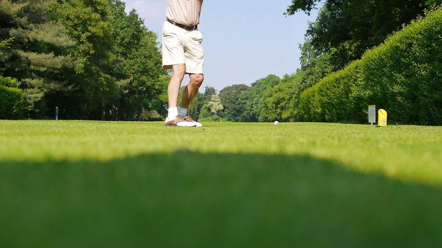 An elder man in shorts playing a drive on a sunny day at a golf course. 