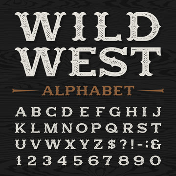 Western style retro distressed alphabet vector font. Serif type dirty letters, numbers and symbols on a dark wood textured background. Vintage vector typography for labels, headlines, posters etc.