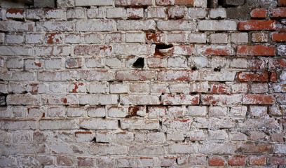 Old dirty brick wall with peeling white paint. 