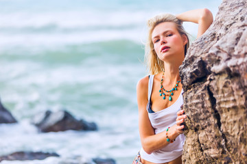 Beautiful young blonde woman posing outdoor at the rocky sea shore