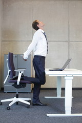 business man stretching in standing position at desk