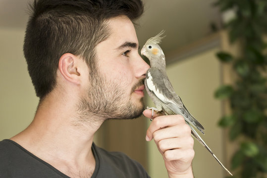 Attractive man playing with his parrot indoors