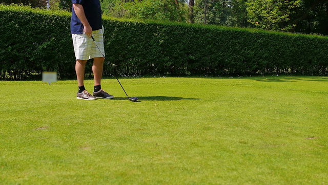 A man dressed in a white short playing a drive at a golf course on a sunny and warm day. 