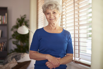 Cheerful grandmother standing next to the window