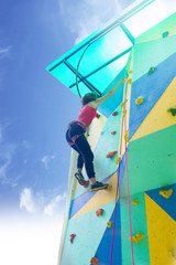 Girl exercise climbing on a artificial rock outdoors