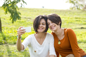 Two Beautiful Young Woman Taking Their Photo In Park