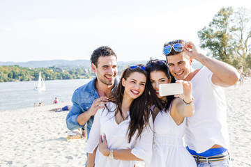 Group of cheerful and beautiful young people taking photos of th