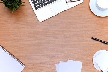 Office table with laptop, notepad and coffee cup. View from above with copy space