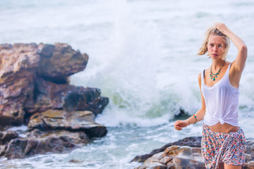 Fototapeta na wymiar Beautiful young blonde woman posing outdoor at the rocky sea shore