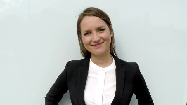 Business woman smiling tat camera and look around in the city by white glass wall.