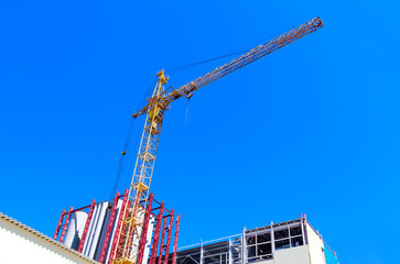 tower crane/ fragments of industrial buildings and a tower crane against the blue sky