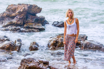 Beautiful young blonde woman posing outdoor at the rocky sea shore
