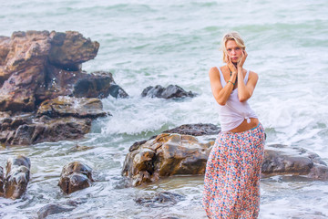 Beautiful young blonde woman posing outdoor at the rocky sea shore