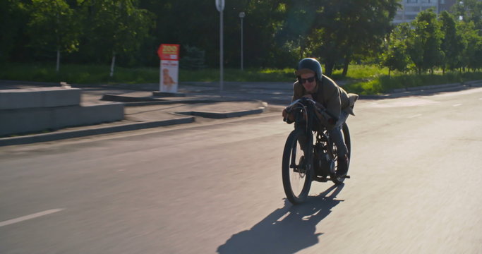 Hipster riding retro moped along city road 