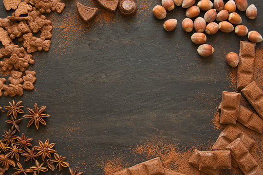 Chocolate, cookies, cocoa, candies and nuts on dark wooden background