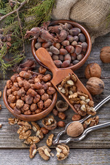 Hazelnuts and walnuts on a spoon and in a linen sack on an old wooden table