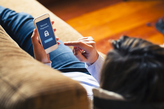 Woman using mobile for payment at home. Blue screen. Secure Payment in the screen.