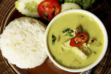 Thai green curry soup and some rice decorated on wooden background, Thai food.