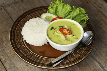 Thai green curry soup and some rice decorated on wooden background, Thai food.