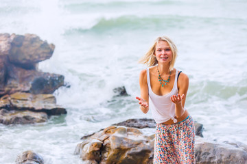 Beautiful young blonde woman posing outdoor at the rocky sea shore