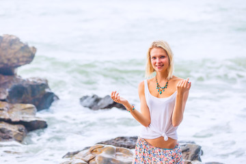 Beautiful young blonde woman posing outdoor at the rocky sea shore
