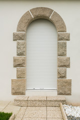 Haustür mit geschlossenem Rollladen und Türeinfassung aus Granit