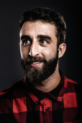 Portrait of a happy young man with beard smiling against gray ba