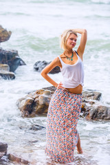 Beautiful young blonde woman posing outdoor at the rocky sea shore