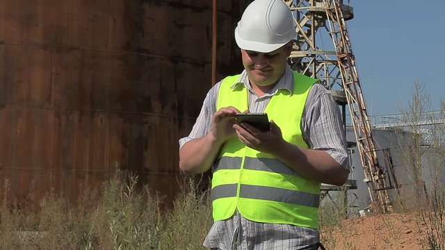 Happy Engineer using tablet PC near to the tanks