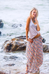 Beautiful young blonde woman posing outdoor at the rocky sea shore
