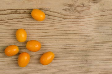 Oval kumquats on old spruce wood board. Closeup. Macro photo from above.