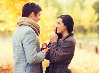 Fototapeta premium smiling couple with red gift box in autumn park