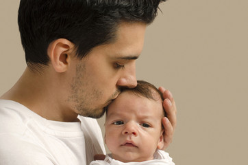 Loving father kissing his new born baby. Father kissing his baby boy forehead and holding him. Parent love.