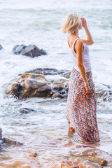 Beautiful young blonde woman posing outdoor at the rocky sea shore