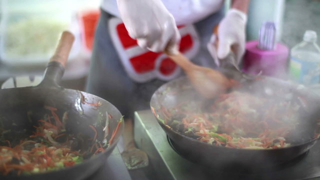 Cooks prepare Chinese noodles with vegetables on a street