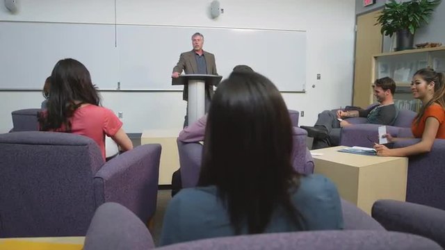 A professor speaking to his students in a study room
