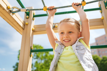 Fototapeta premium happy little girl climbing on children playground