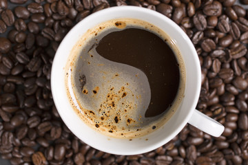 Still life of fresh roasted coffee beans with a white mug on a black slate surface