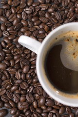 Still life of fresh roasted coffee beans with a white mug on a black slate surface