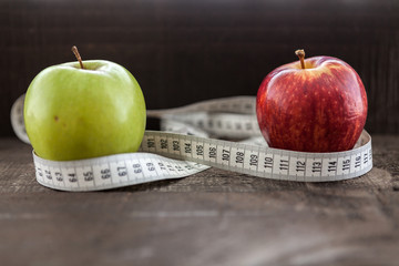  apple surrounded by a measuring tape referring to diet and health concept on wooden background
