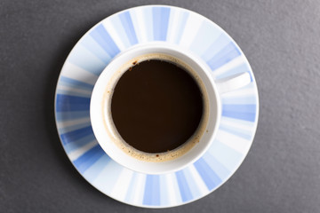 Freash coffee in a cup and saucer on a black slate work surface