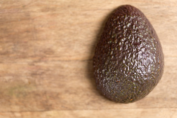 Fresh avocado slice on a wooden kitchen work surface displaying the texture of its skin