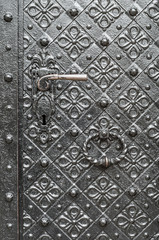 Old iron door reinforced with decorative steel belts painted black