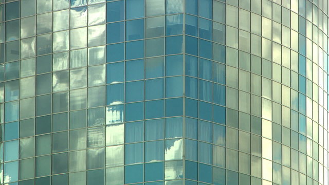 Tall mirrored skyscraper reflects the clouds going by in a timelapse