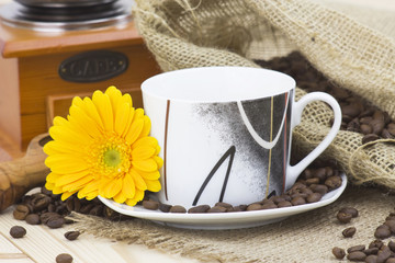 cup of coffee with yellow gerbera and coffee beans