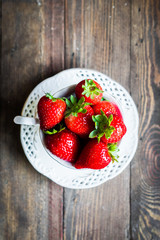 Fresh strawberries in a cup on wooden background