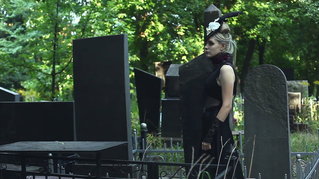 Between the graves in the cemetery walks lady. Gothic look.
