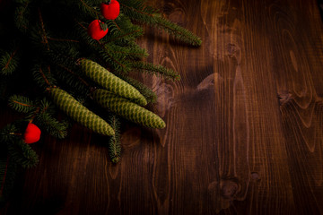 Spruce branch and tiny red apples on wooden planks