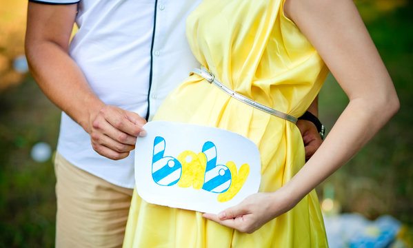 Future parents hold the plate with an inscription near a stomach