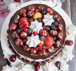 Cake decorated with chocolate, meringues and fresh berries